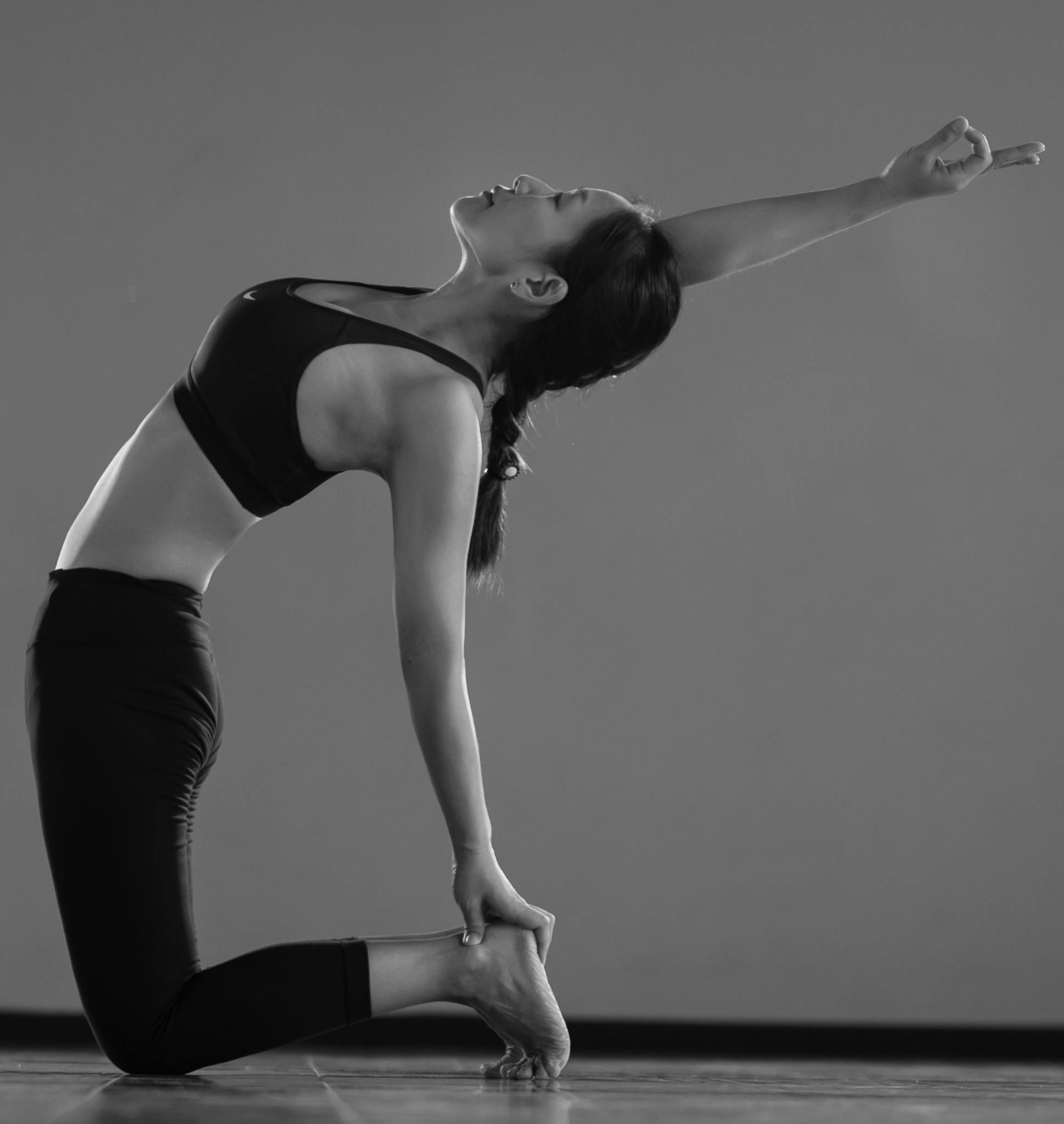 Grayscale yoga backbend pose, arm extended upward